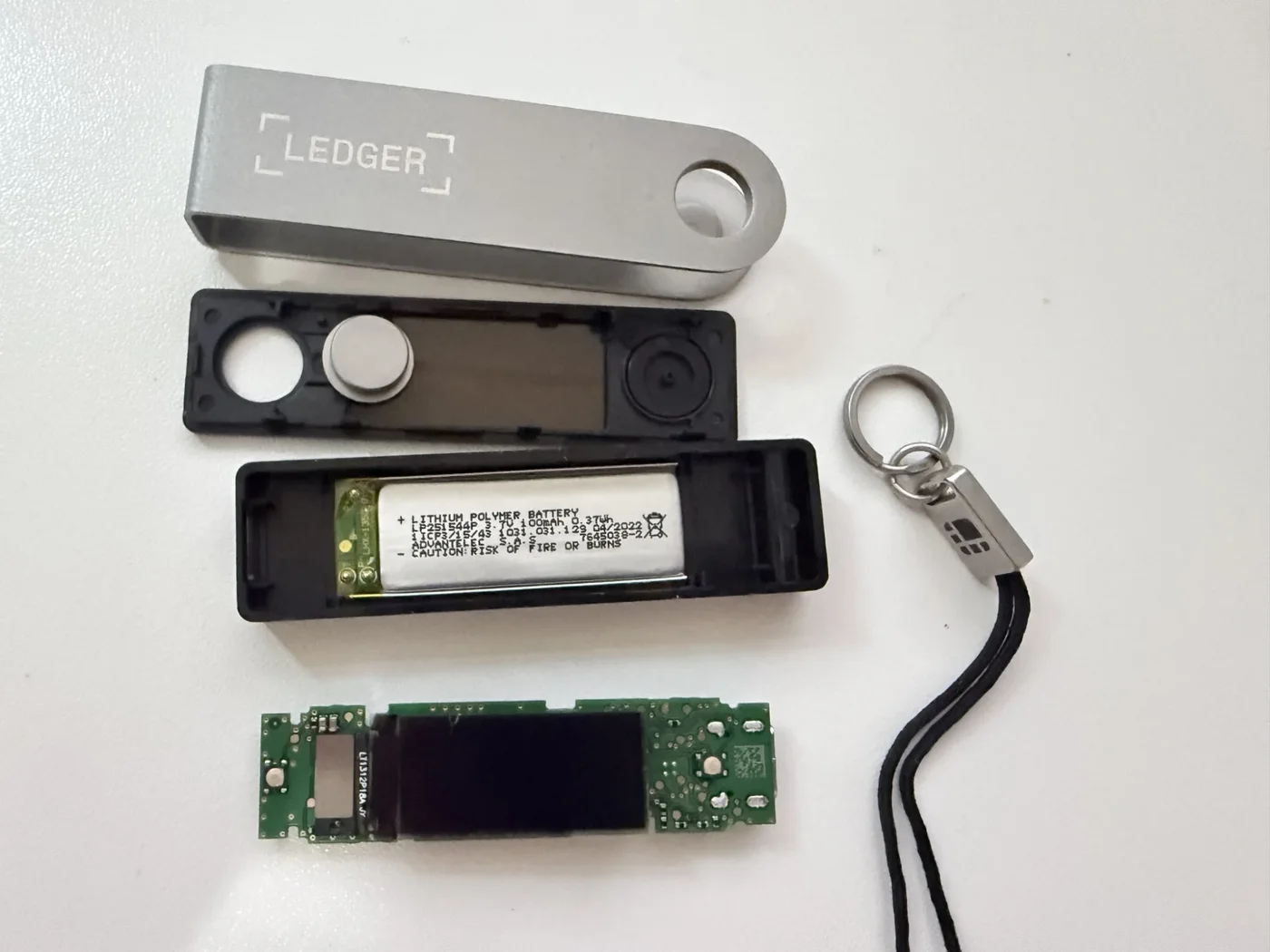 Interior de un Ledger Nano X intacto, cara de la pantalla: la placa verde muestra solo la pantalla OLED negra y su conector plano, sin ninguna placa ni componente extra bajo la pantalla
